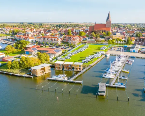 Blick auf Barth an der Ostsee mit Yachthafen, Wohnmobilstellplätzen und modernen Ferienhäusern am Wasser.