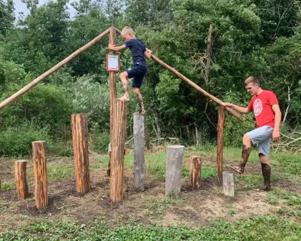 Junge und Mann balancieren auf Baumstämmen im Kletterpark Plau am See.