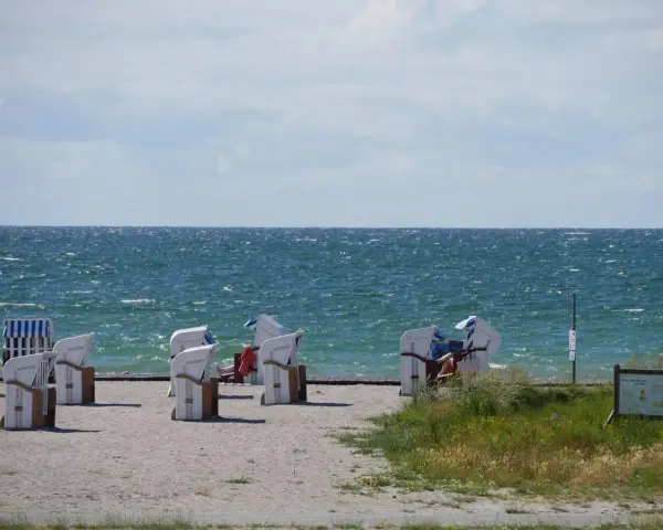 Strandkörbe am Bojendorfer Strand laden zum Entspannen ein. Das Meer glitzert, die Wolken ziehen vorbei.