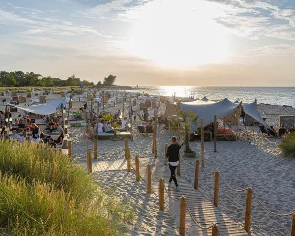 Sommerliche Ostsee Party mit vielen Gästen, Strandkörben und Zelten am Abend.