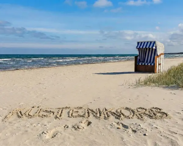 Der Juliusruh Strand lädt mit einer Strandmuschel und dem Schriftzug "KUSTENKORS" im Sand zum Verweilen ein.