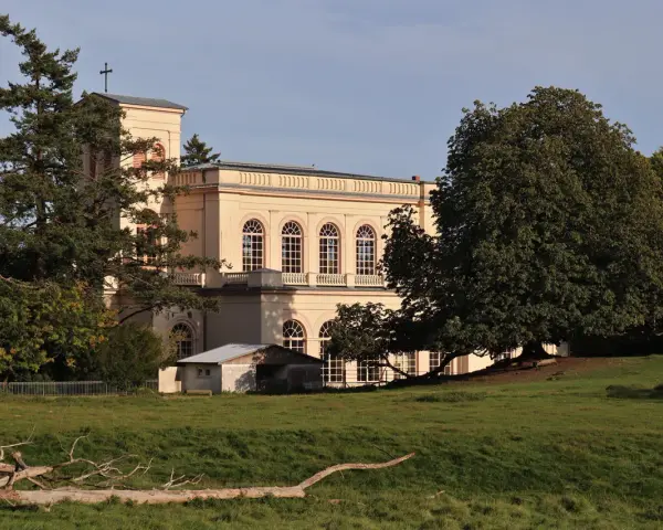 Prachtvolles Gebäude in der **Putbus Altstadt** mit Kirchturm und großen Rundbogenfenstern, umgeben von Bäumen und einer grünen Wiese.