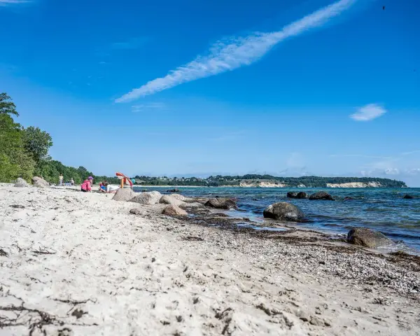 Kinder spielen am lobbe strand. Sand, Steine und das Meer bilden eine idyllische Szene unter blauem Himmel.