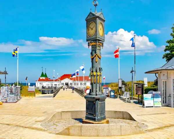 Prachtvoller Uhrenturm im Ahlbeck Zentrum, flankiert von Souvenirbuden und wehenden Flaggen.