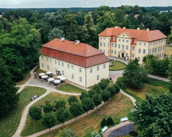 Zwei gelbe Barockschlösser mit roten Dächern auf der Schlossinsel Mirow, umgeben von üppigem Grün und gepflegten Wegen.