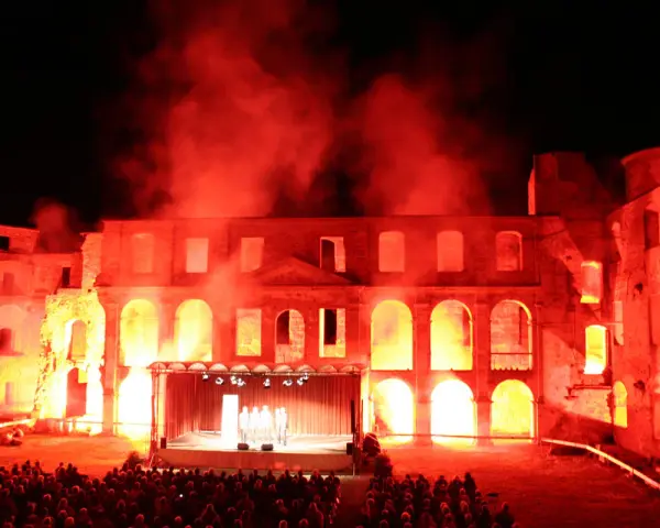 Spektakuläre Inszenierung im Schloss Dargun: Eine Bühne vor der Ruine, beleuchtet von rotem Licht und Nebel, lockt ein großes Publikum zu den Veranstaltungen.