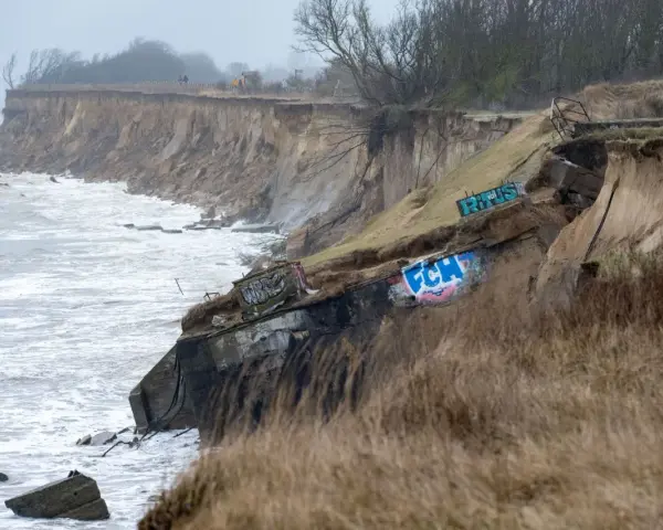 Ein alter Bunker am Strand, von der Erosion freigelegt und mit Graffiti bemalt, trotzt den Wellen.