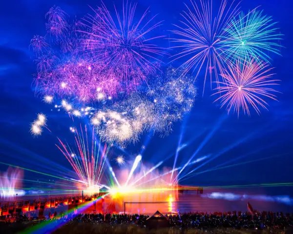 Spektakuläres Feuerwerk und Lichtshow an der Ostsee. Menschen feiern Silvester mit einer ausgelassenen Party am Strand.