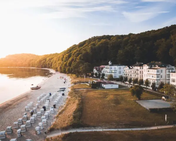 Sonnenuntergang am Binz Strand mit vielen Strandkörben, weißen Villen und einem dichten Wald.