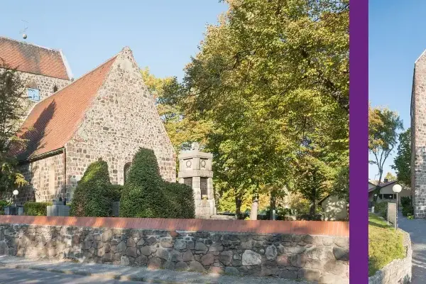 Die alte Dorfkirche mit ihrem markanten Turm und roten Ziegeldach, umgeben von Bäumen im Herbstlaub.