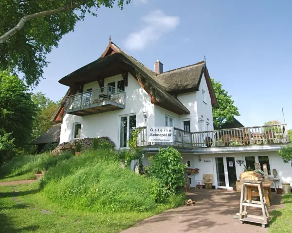 Galerie "Schnepel III" mit Kunsthandwerk und Veranstaltungen. Ein charmantes Haus mit Reetdach und Balkon.
