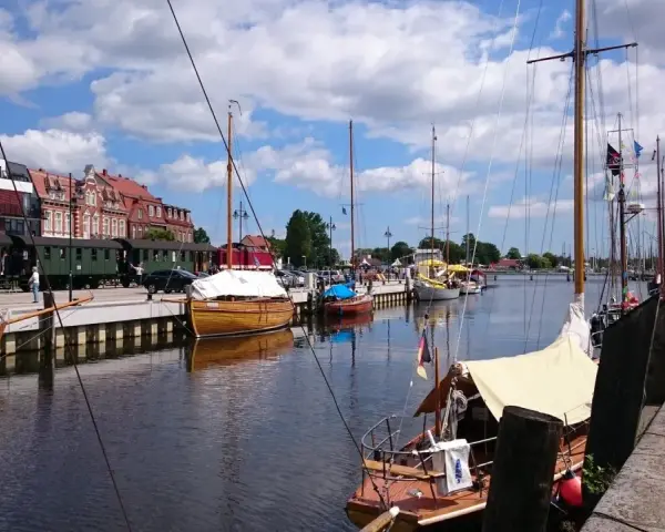 Boote im Greifswald Hafen liegen neben historischen Zügen.