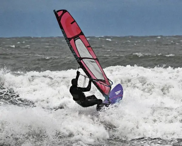 Windsurferin in Aktion auf der Ostsee, die mit ihrem Segel über die Wellen springt.