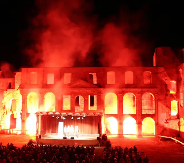 Spektakuläre Inszenierung im Schloss Dargun: Eine Bühne vor der Ruine, beleuchtet von rotem Licht und Nebel, lockt ein großes Publikum zu den Veranstaltungen.