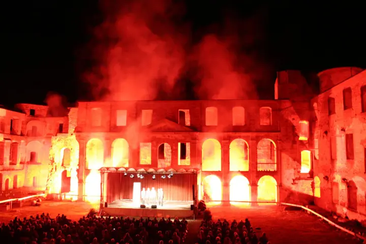 Spektakuläre Inszenierung im Schloss Dargun: Eine Bühne vor der Ruine, beleuchtet von rotem Licht und Nebel, lockt ein großes Publikum zu den Veranstaltungen.