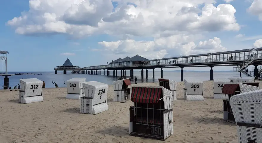 Strandkörbe am Zirchow Strand, mit Seebrücke und Wolkenhimmel.