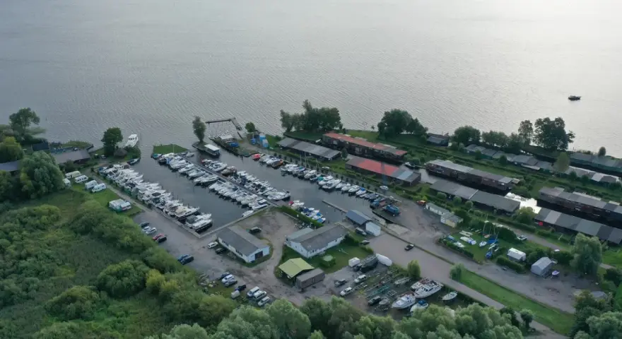 Luftaufnahme des Hafens Plau am See mit vielen Booten, Wohnmobilen und Gebäuden. Ein lebendiges Hafenfest-Flair liegt in der Luft.