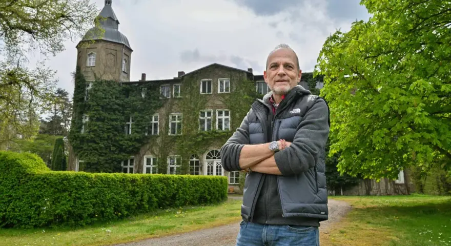 Mann vor dem historischen Gutshaus Wesselstorf, das von Efeu umrankt ist.