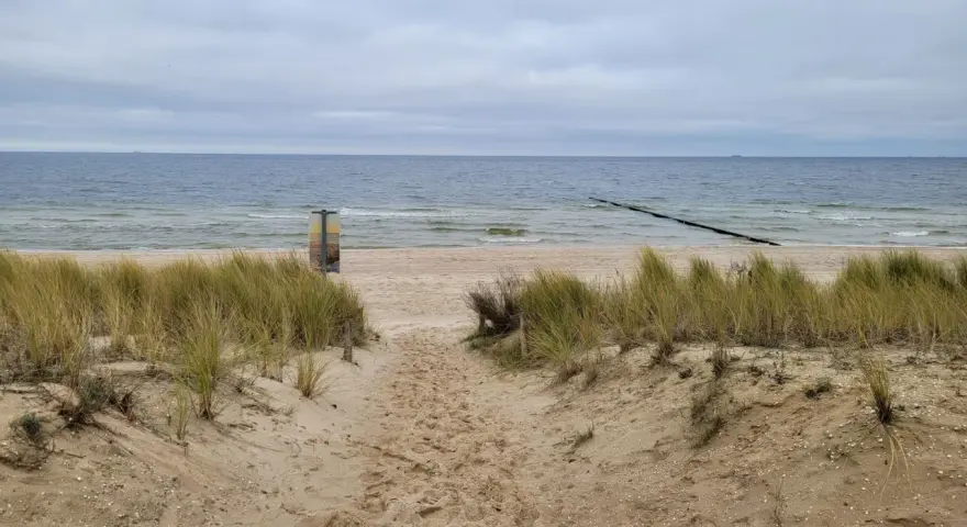 Pfad durch Dünen zum Strand Bansin. Das Meer ist ruhig, der Himmel bedeckt.