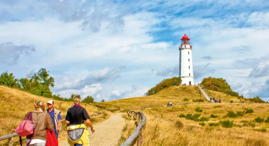 Wanderweg zum Leuchtturm Dornbusch auf Hiddensee Vitte. Menschen spazieren auf einem Feldweg durch trockenes Gras.