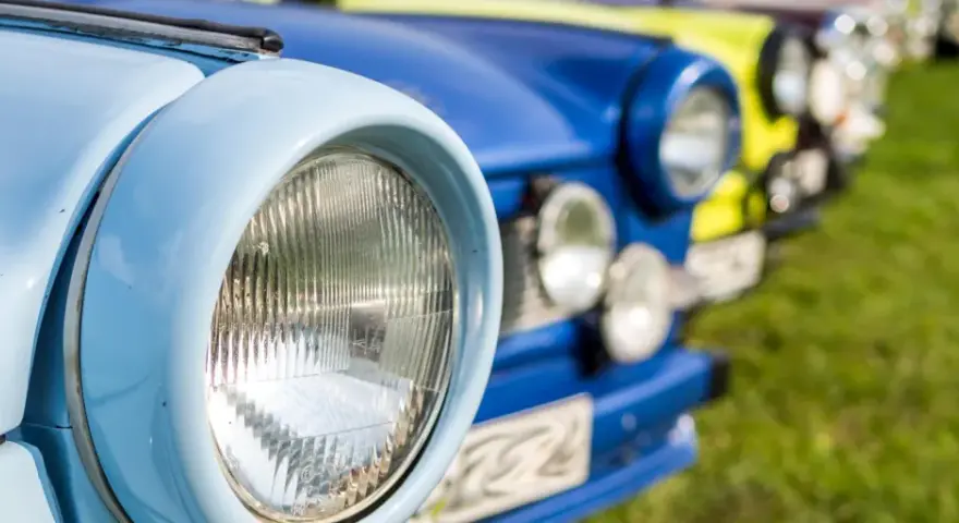 Bunte Oldtimer reihen sich auf einer Wiese bei einem Oldtimertreffen in Mecklenburg-Vorpommern.