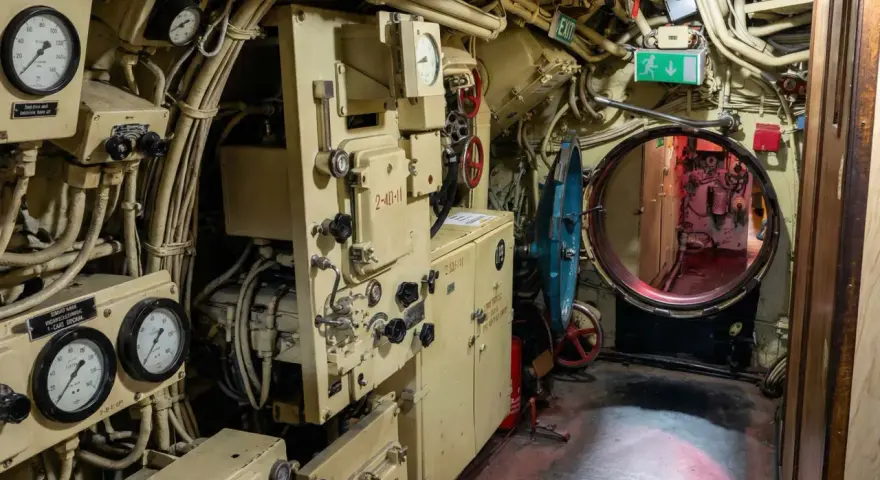Blick in das Innere des U-Bootes U 461. Messinstrumente, Rohre und ein Notausgangsschild sind zu sehen.