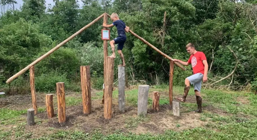 Junge und Mann balancieren auf Baumstämmen im Kletterpark Plau am See.