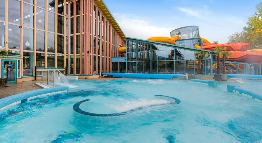 Einladende Therme an der Ostsee mit großem Pool und bunten Wasserrutschen im Hintergrund.