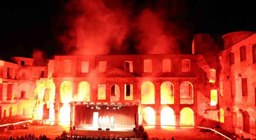 Spektakuläre Inszenierung im Schloss Dargun: Eine Bühne vor der Ruine, beleuchtet von rotem Licht und Nebel, lockt ein großes Publikum zu den Veranstaltungen.