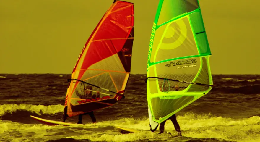 Zwei Windsurfer mit bunten Segeln auf dem Meer. Ein tolles Erlebnis für Surf und Segel Hiddensee.