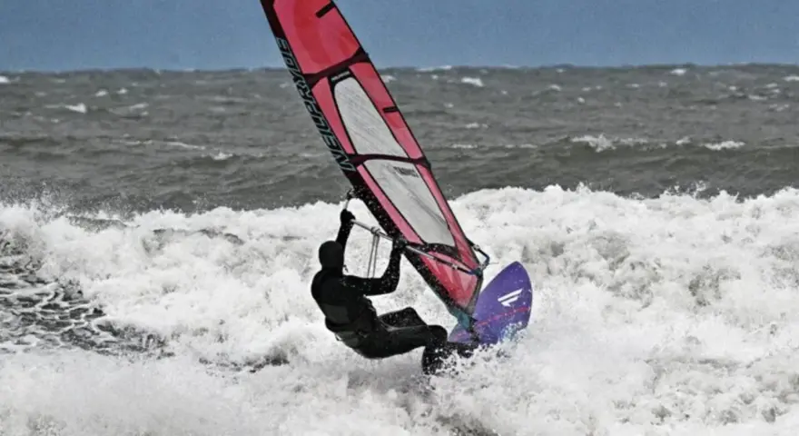 Windsurferin in Aktion auf der Ostsee, die mit ihrem Segel über die Wellen springt.