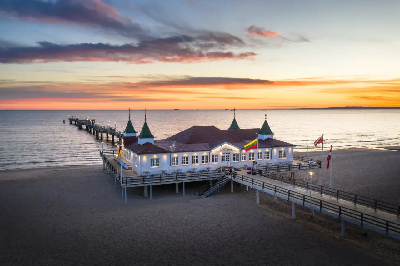 Das Ahlbeck Zentrum mit seiner Seebrücke bei Sonnenuntergang. Der Himmel leuchtet in warmen Farben über dem Meer.