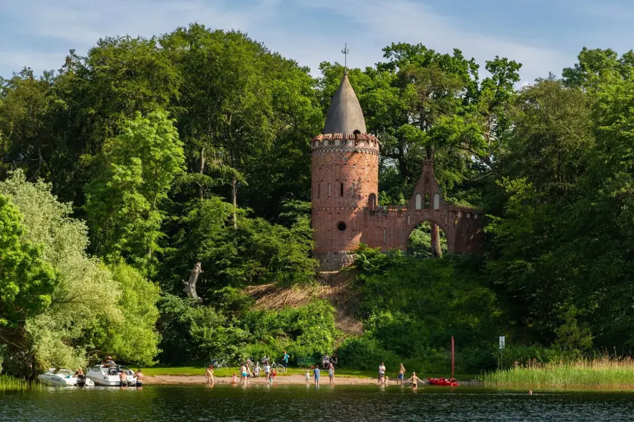 Ein versteckter Turm am Seeufer, umgeben von Bäumen. Ein idyllischer Ort für Sommerfreuden und Schwerin Geheimtipps.