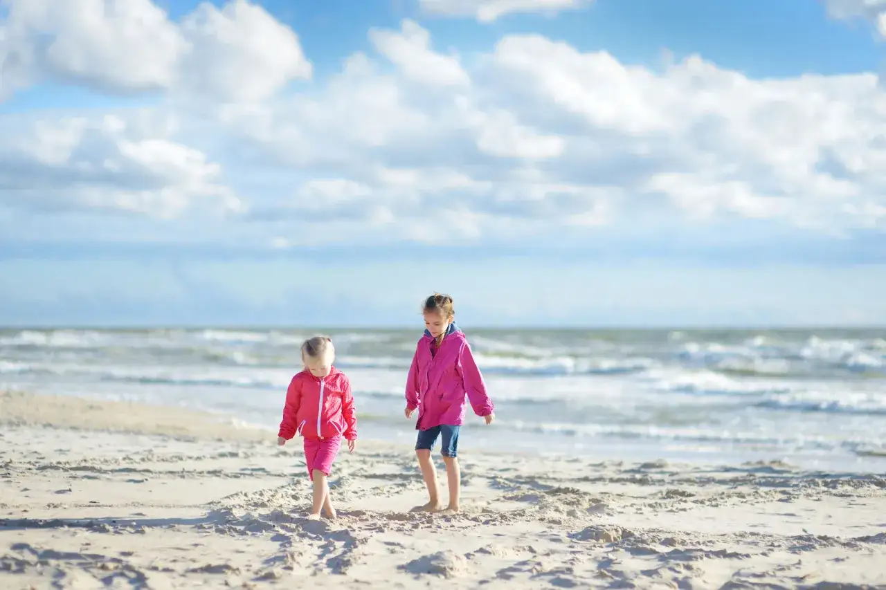 Zwei Mädchen in pinken Jacken erkunden den Strand. Ein schöner Tag für Veranstaltungen MV Kinder.