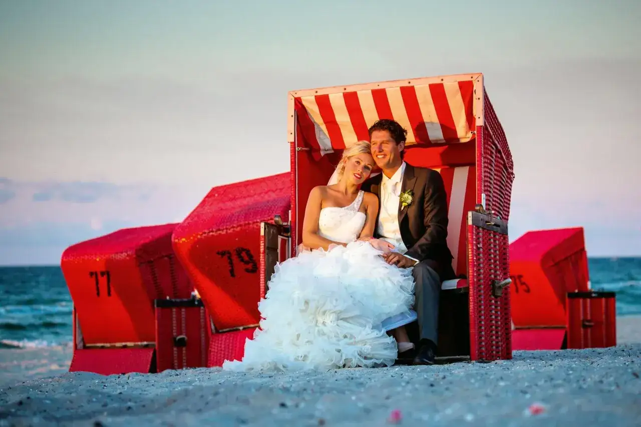 Glückliches Brautpaar sitzt in einer Strandkorb. Sie haben beschlossen, am Strand zu heiraten.