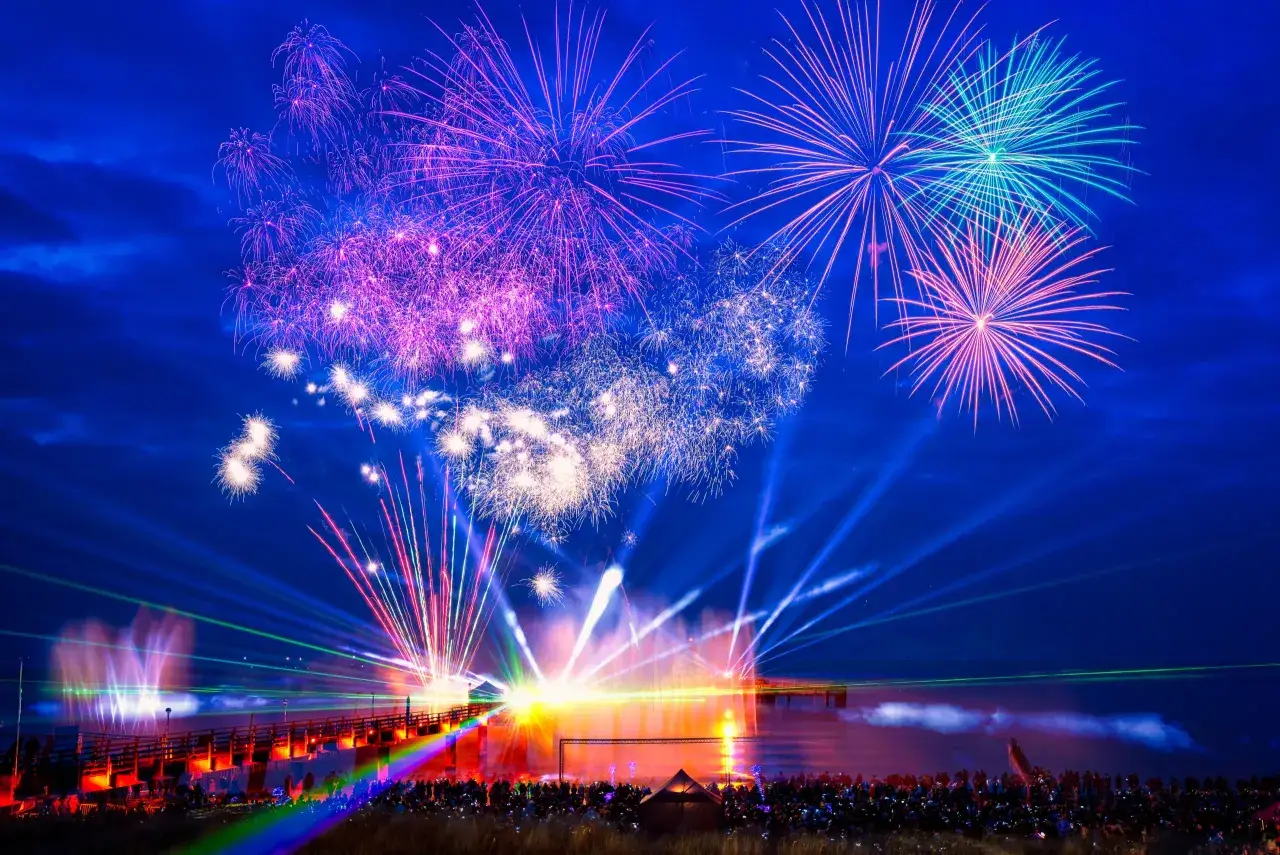 Buntes Feuerwerk &uuml;ber der Ostsee bei einer Silvesterparty. Menschen stehen am Ufer und blicken auf die Lichtershow.