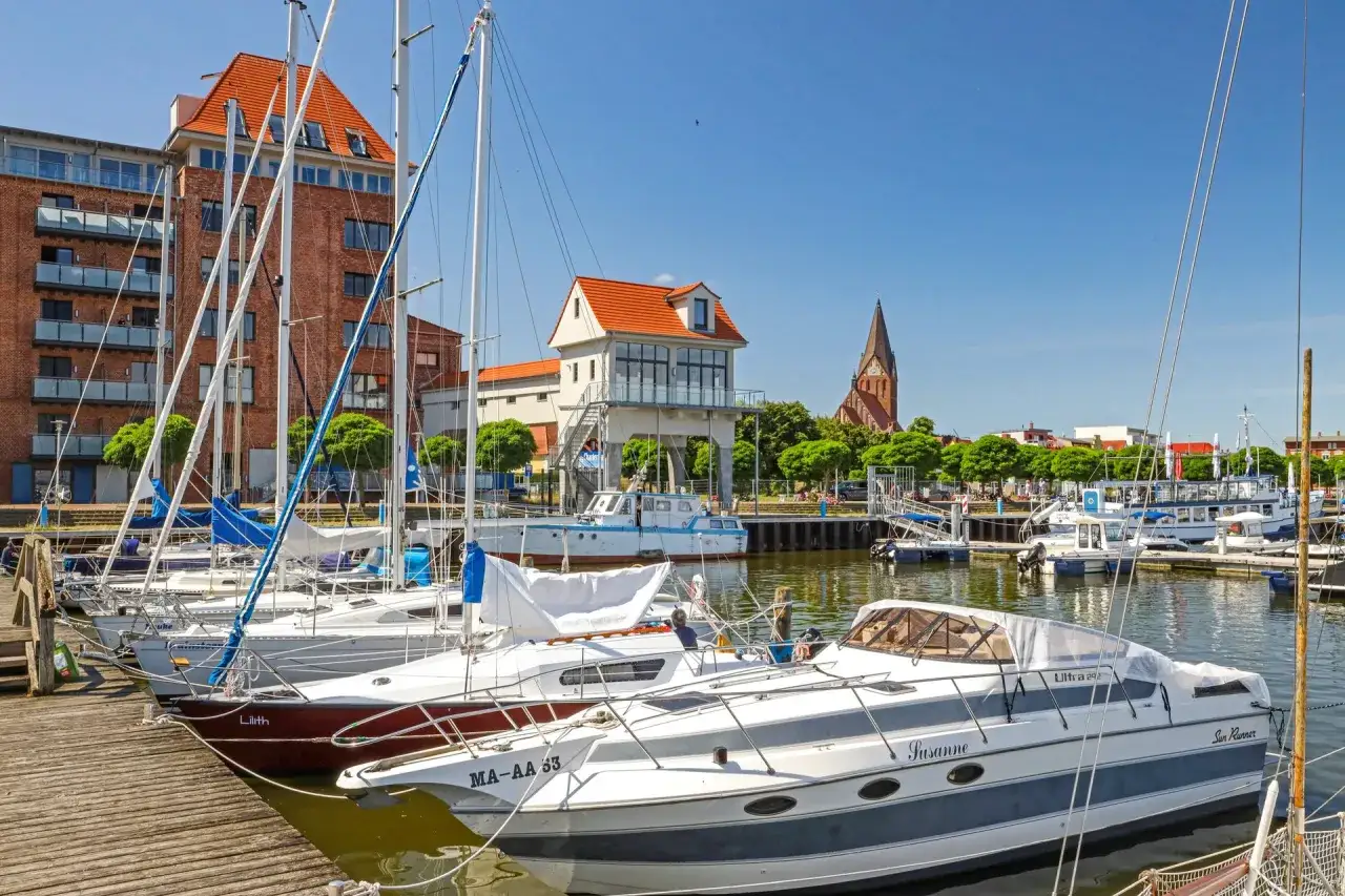 Segelboote und Yachten im Hafen von Barth an der Ostsee. Im Hintergrund rote Backsteingeb&auml;ude und eine Kirche.