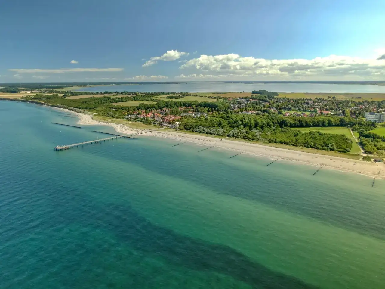 Traumhafte Küstenansicht von Wustrow mit Pier und Strand. Entdecken Sie hier Wustrow Geheimtipps für Ihren Urlaub.