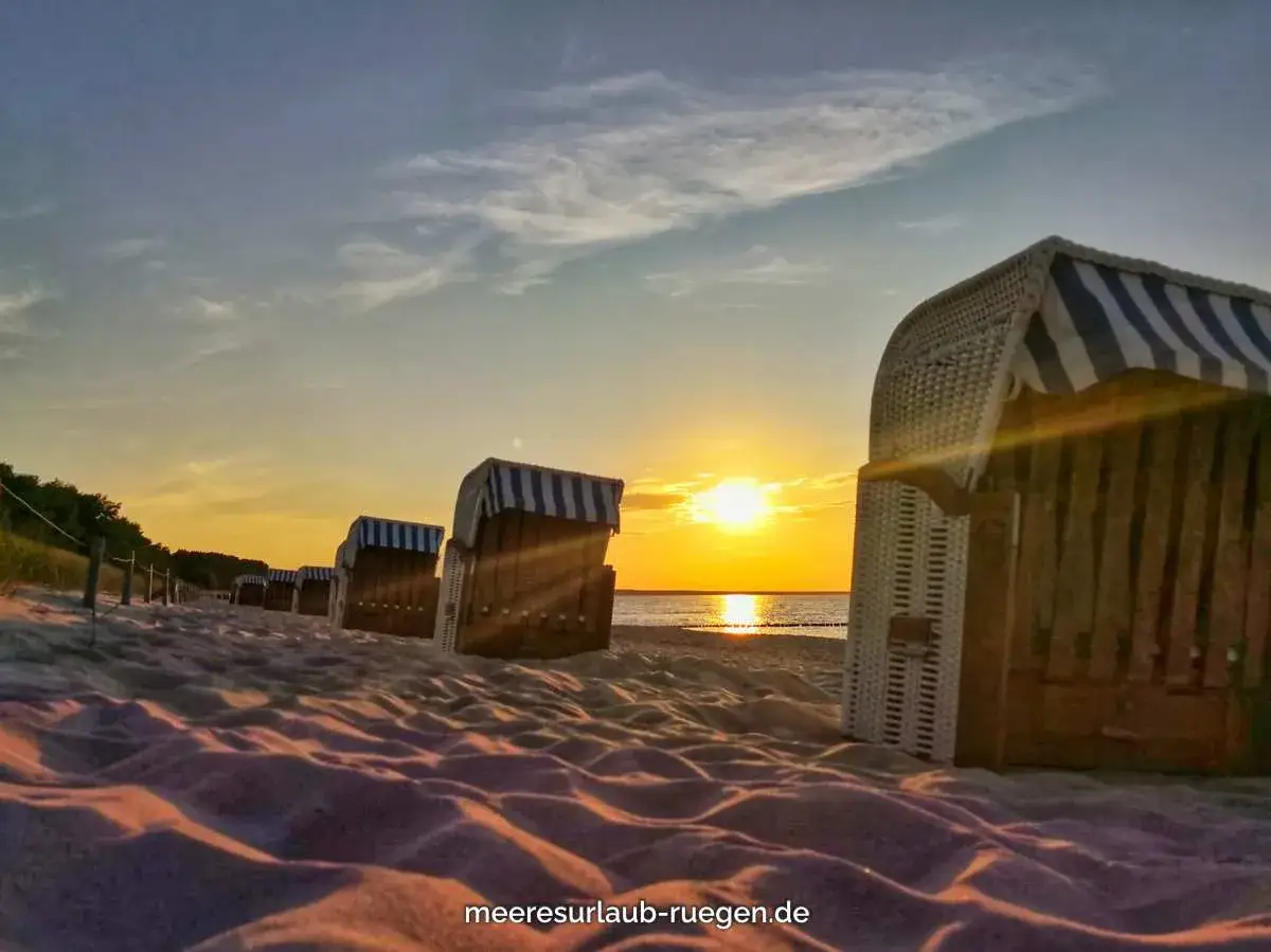 Strandkörbe im Abendlicht, die Sonne versinkt im Meer. Ein friedlicher glowe hafen.