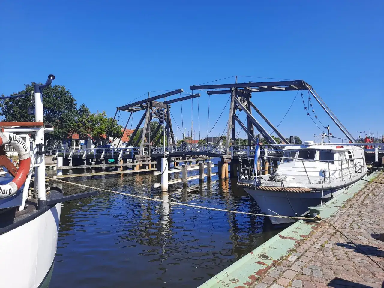 Ein Boot liegt im Greifswald Hafen vor einer historischen Klappbrücke.