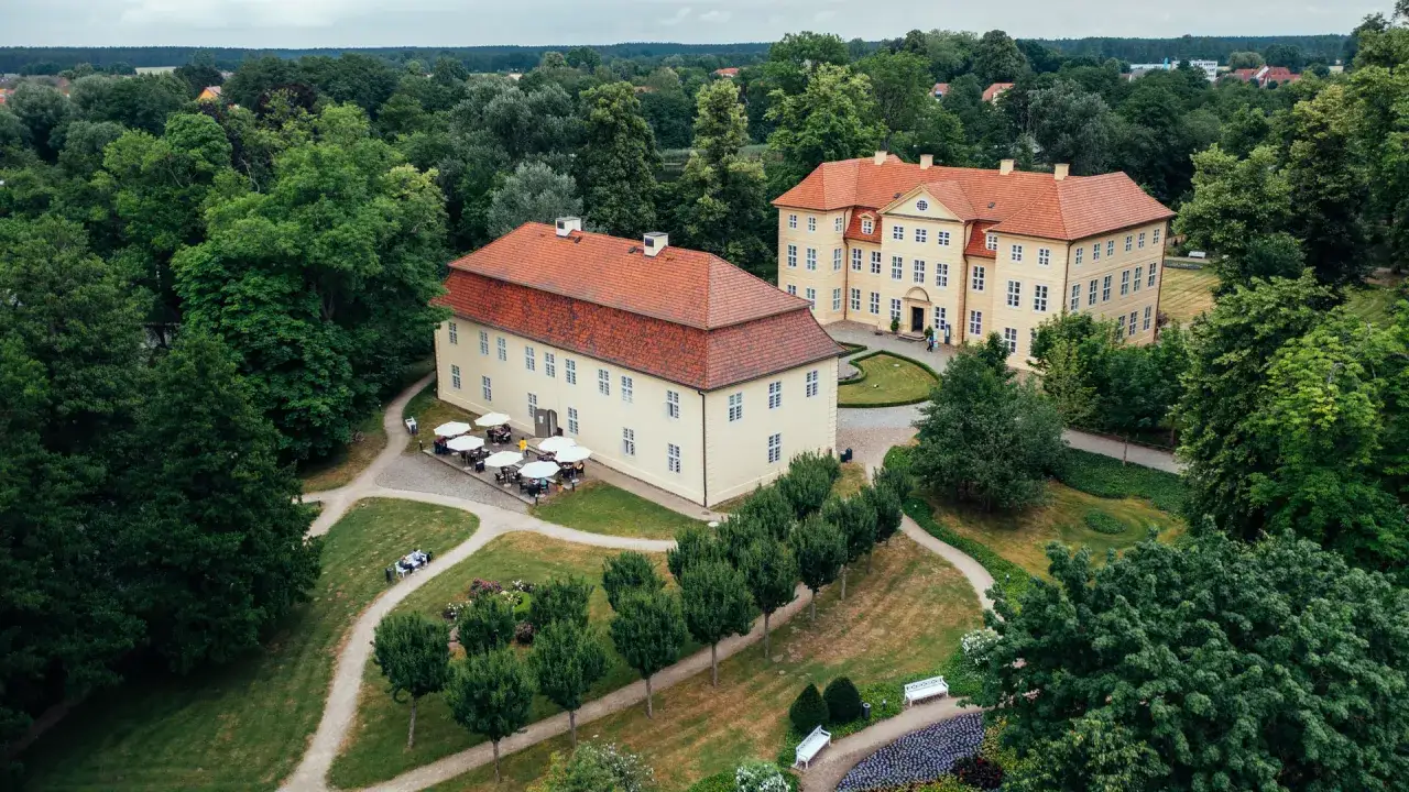 Zwei gelbe Schlösser mit roten Dächern, umgeben von üppigem Grün. Ein idyllischer Ort, der an die Liebesinsel Mirow erinnert.