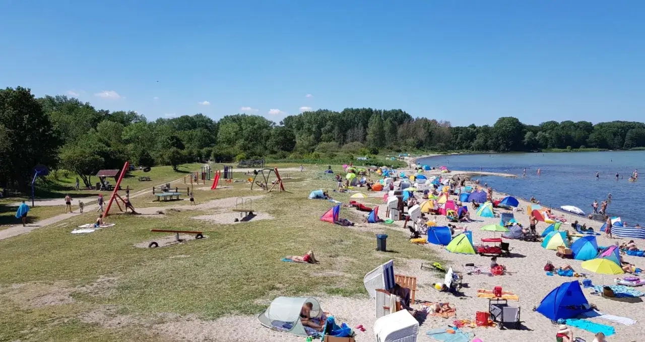 Sonniger Tag am Zierow Strand mit vielen bunten Zelten, spielenden Kindern und Badegästen im Wasser.