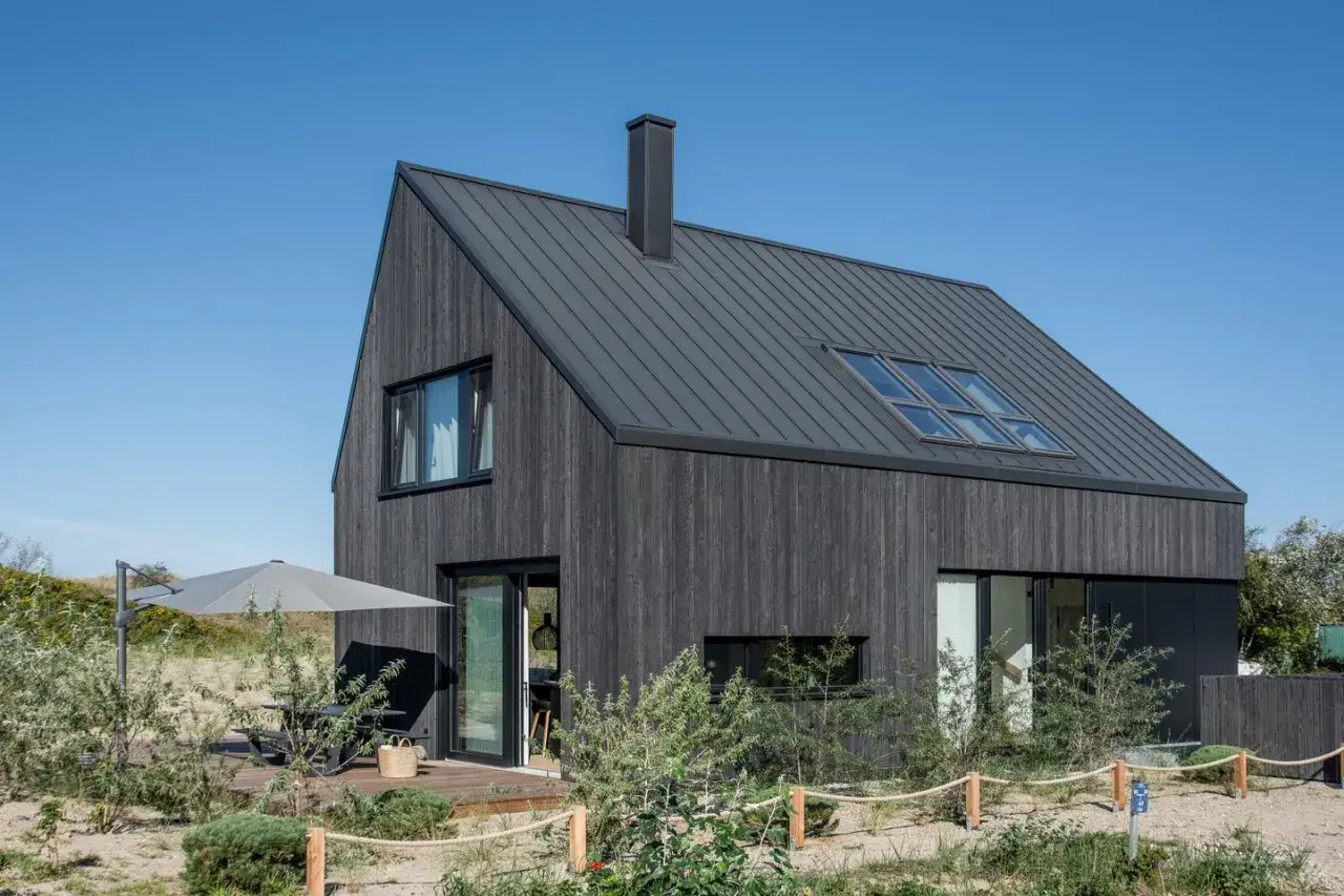 Modernes Holzhaus am Dierhagen Strand mit Terrasse und Sonnenschirm.