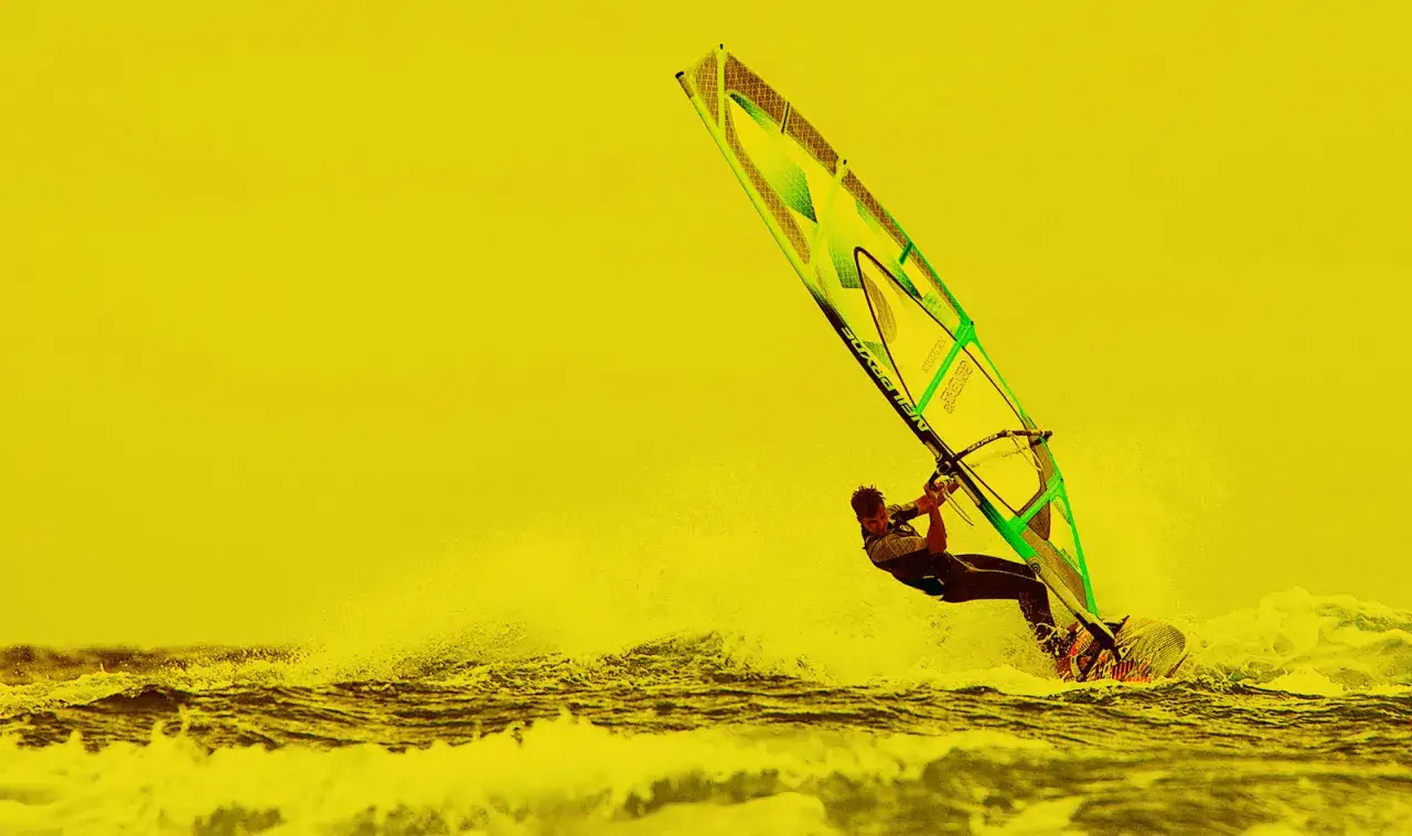 Windsurfer auf Hiddensee, der mit voller Kraft über die Wellen gleitet. Ein echtes Abenteuer bei Surf und Segel Hiddensee.