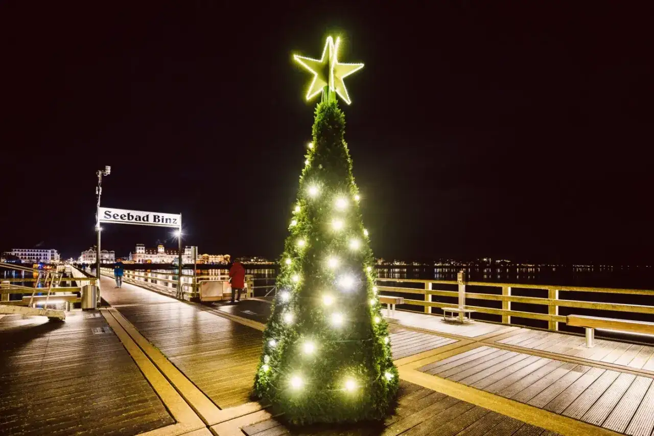 Ein beleuchteter Weihnachtsbaum auf einem Steg in Binz, der an einen Weihnachtsmarkt Mecklenburgische Seenplatte erinnert.