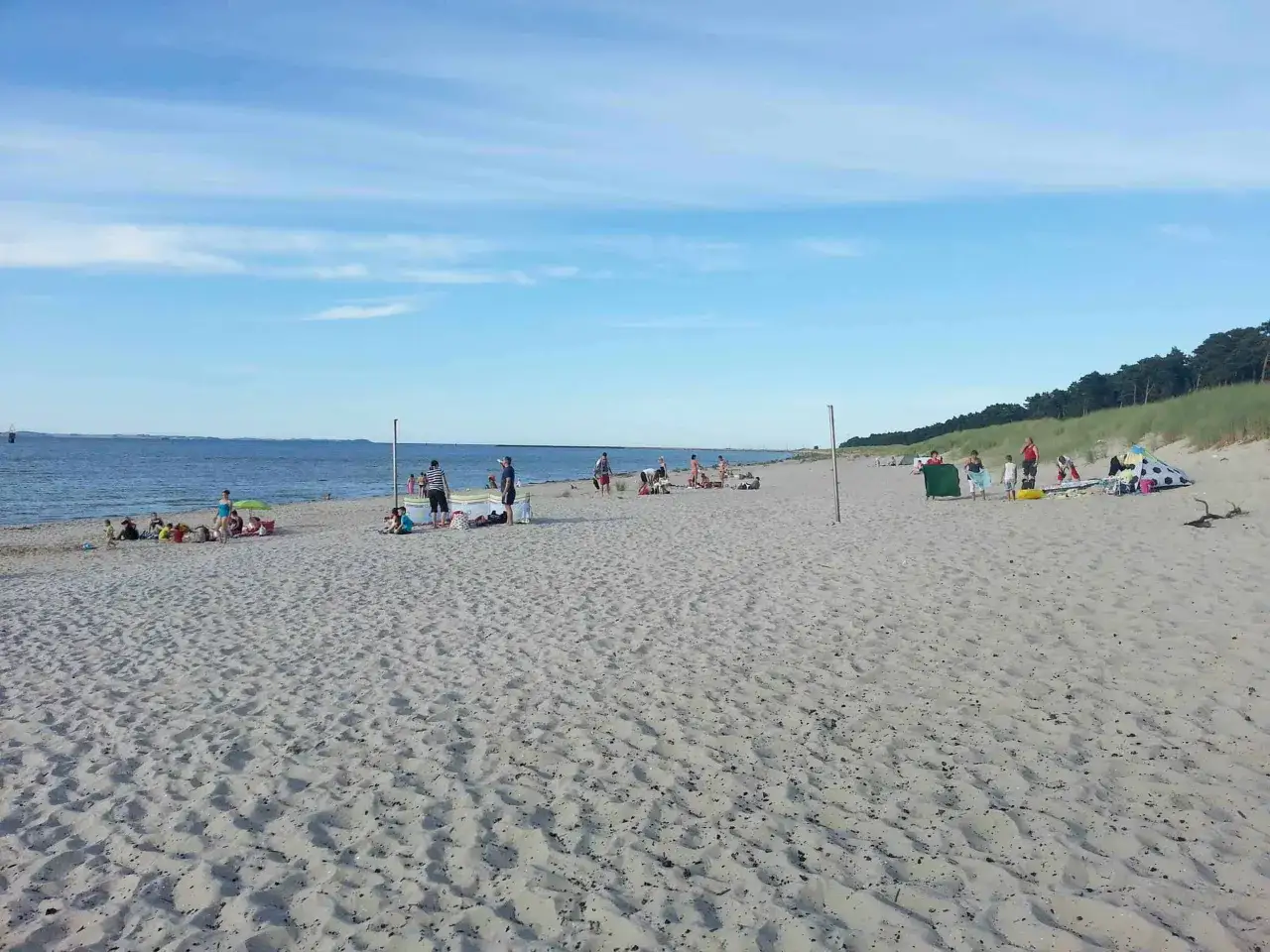 Menschen genießen einen sonnigen Tag am lubmin strand. Das Meer ist ruhig, der Himmel blau mit wenigen Wolken.