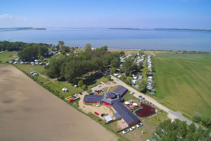 Luftaufnahme des pepelow campingplatzes mit Wohnmobilen, Bäumen und einem See im Hintergrund.