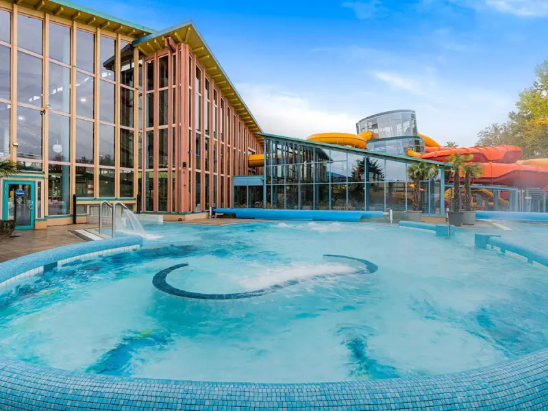 Einladende Therme an der Ostsee mit großem Pool und bunten Wasserrutschen im Hintergrund.